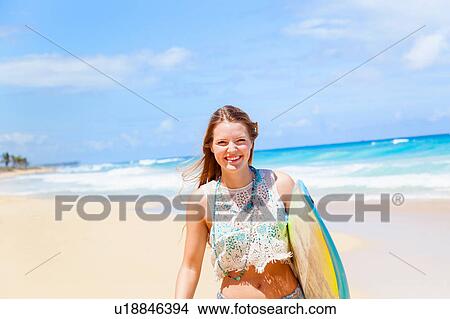 Portrait of young woman carrying surfboard on beach, Dominican Republic, The Caribbean View Large Photo Image Picture - Portrait of young woman carrying surfboard on beach, Dominican Republic, The Caribbean. Fotosearch