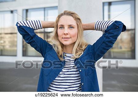 Portrait of young woman outdoors, hands behind head View Large Photo Image Picture - Portrait of young woman outdoors, hands behind head. Fotosearch