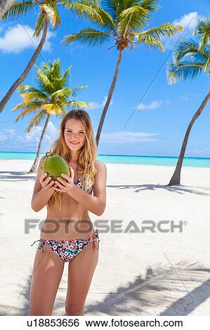 Portrait of young woman wearing bikini holding coconut on beach, Dominican Republic, The Caribbean View Large Photo Image Stock Photograph - Portrait of young woman wearing bikini holding coconut on beach, Dominican Republic, The Caribbean. Fotosearch