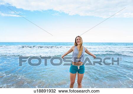 Stock Image - Portrait of young woman with arms open in sea, Dominican Republic, The Caribbean. Fotosearch