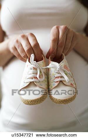 Pregnant woman holding baby shoes View Large Photo Image Stock Image - Pregnant woman holding baby shoes. Fotosearch
