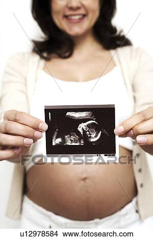 Picture - Pregnant woman holding her baby scan. Fotosearch