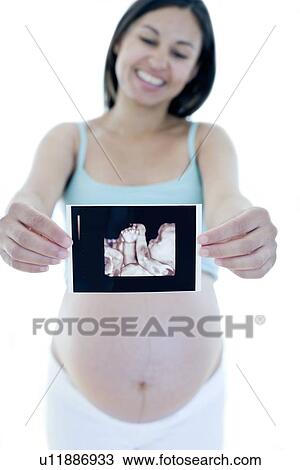 Stock Image - Pregnant woman holding her baby scan. Fotosearch