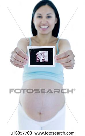Stock Image - Pregnant woman holding her baby scan. Fotosearch