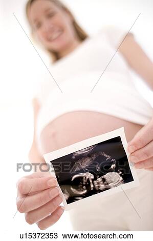 Stock Image - Pregnant woman holding her baby scan. Fotosearch
