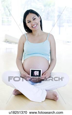 Stock Image - Pregnant woman holding her baby scan. Fotosearch