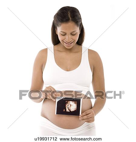 Stock Image - Pregnant woman holding her baby scan. Fotosearch