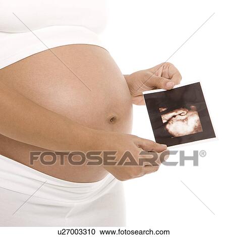 Stock Image - Pregnant woman holding her baby scan. Fotosearch