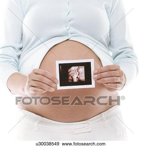 Stock Photo - Pregnant woman holding her baby scan. Fotosearch