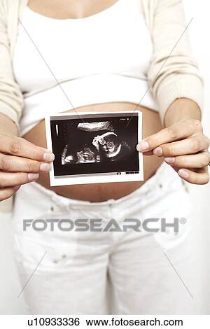 Stock Photograph - Pregnant woman holding her baby scan. Fotosearch
