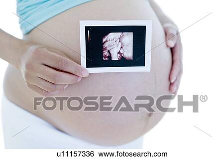 Stock Photograph - Pregnant woman holding her baby scan. Fotosearch