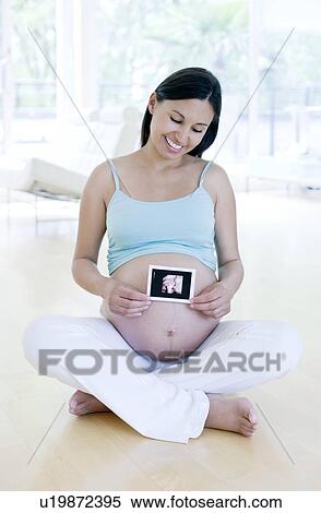 Stock Photography - Pregnant woman holding her baby scan. Fotosearch