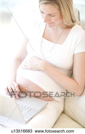 Stock Image - Pregnant woman using a laptop. Fotosearch