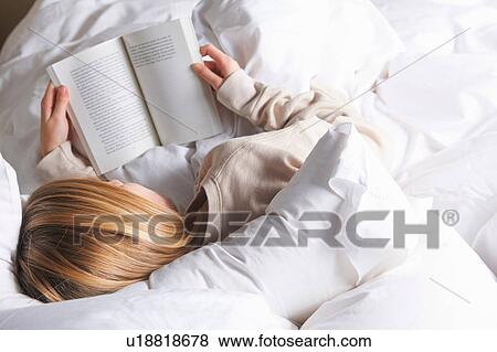 Rear view of blond haired girl reading book in bed View Large Photo Image Stock Photo - Rear view of blond haired girl reading book in bed. Fotosearch