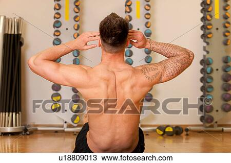 Rear view of man in gym doing sit ups View Large Photo Image Stock Image - Rear view of man in gym doing sit ups. Fotosearch