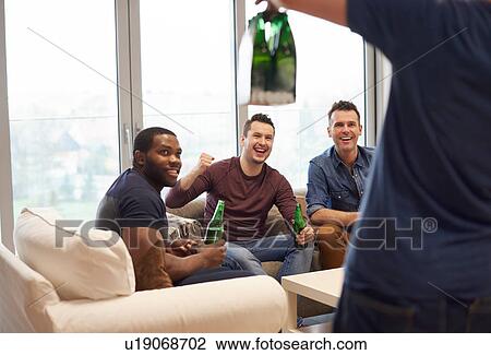 Stock Image - Rear view of man showing smiling friends beers. Fotosearch