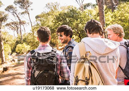 Stock Photo - Rear view of man talking on smartphone whilst hiking with friends in forest, Deer Park, Cape Town, South Africa. Fotosearch