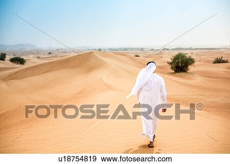 Rear view of middle eastern man wearing traditional clothes walking in desert, Dubai, United Arab Emirates View Large Photo Image Stock Photo - Rear view of middle eastern man wearing traditional clothes walking in desert, Dubai, United Arab Emirates. Fotosearch
