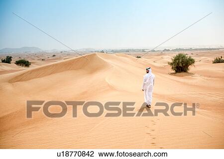 Rear view of young middle eastern man wearing traditional clothes walking in desert, Dubai, United Arab Emirates View Large Photo Image Stock Image - Rear view of young middle eastern man wearing traditional clothes walking in desert, Dubai, United Arab Emirates. Fotosearch