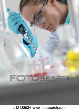 Picture - Researcher pipetting liquid. Fotosearch