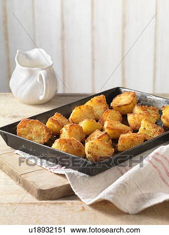 Stock Image - Roast potatoes with crispy seasoning in tray. Fotosearch