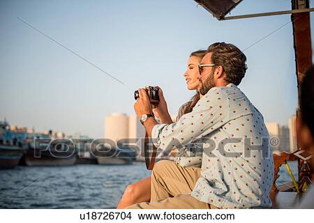 Romantic couple reviewing camera on boat at Dubai marina, United Arab Emirates View Large Photo Image Picture - Romantic couple reviewing camera on boat at Dubai marina, United Arab Emirates. Fotosearch