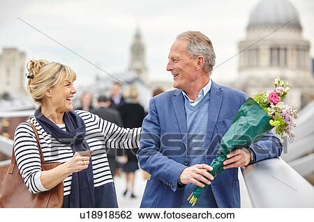 Stock Image - Romantic mature dating couple greeting on Millennium Bridge, London, UK. Fotosearch