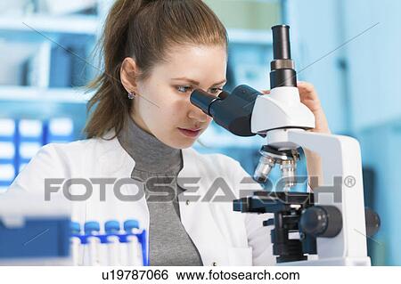 Stock Photograph - Scientist using microscope. Fotosearch