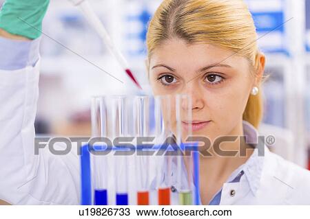Stock Image - Scientist using pipette with test tubes. Fotosearch