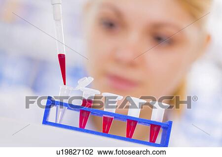 Stock Image - Scientist using pipette with test tubes. Fotosearch