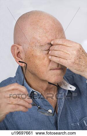 Stock Image - Senior man rubbing his eyes. Fotosearch
