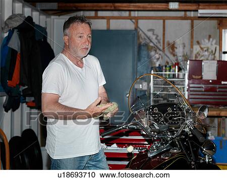 Senior man wiping hands whilst cleaning motorcycle in garage View Large Photo Image Stock Image - Senior man wiping hands whilst cleaning motorcycle in garage. Fotosearch