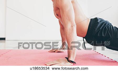 Picture - Side view of man in gym doing push ups. Fotosearch