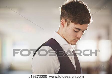 Stock Image - Side view of man wearing waistcoat looking down. Fotosearch
