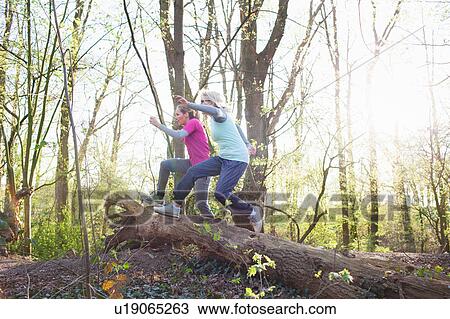 Side view of women in forest jumping over fallen tree View Large Photo Image Stock Image - Side view of women in forest jumping over fallen tree. Fotosearch