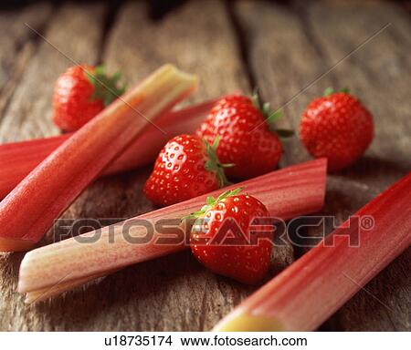 Picture - Strawberries and rhubarb on wooden table, close-up. Fotosearch