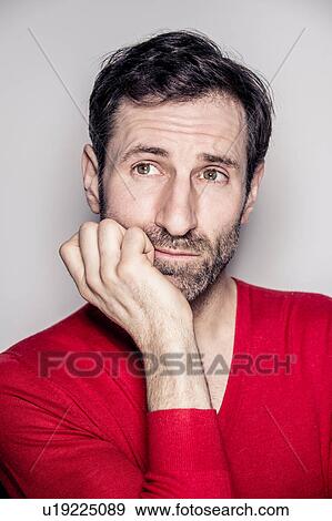 Stock Photo - Studio portrait of mature man wearing red sweater looking sideways. Fotosearch