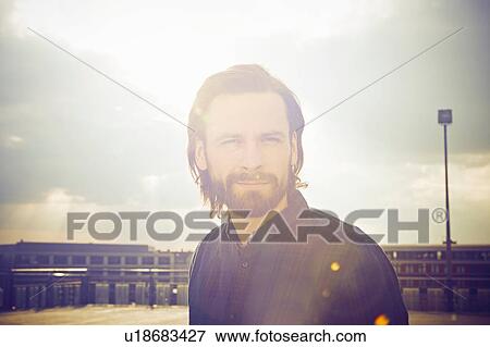 Sunlit portrait of mid adult man on rooftop parking lot View Large Photo Image Stock Photo - Sunlit portrait of mid adult man on rooftop parking lot. Fotosearch