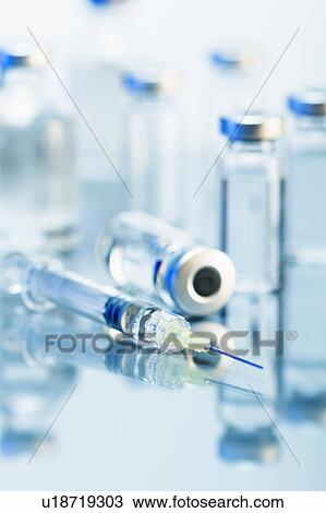 Stock Image - Syringe. Disposable plastic medical syringe surrounded by sealed medication vials. Fotosearch