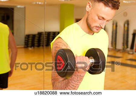 Tattooed man at gym lifting dumbbells View Large Photo Image Stock Photo - Tattooed man at gym lifting dumbbells. Fotosearch