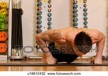 Tattooed man exercising on yoga mat in gym View Large Photo Image Stock Image - Tattooed man exercising on yoga mat in gym. Fotosearch