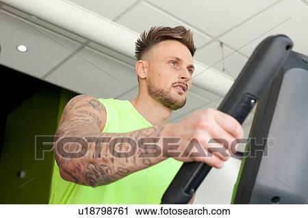 Tattooed man in gym using exercise machine View Large Photo Image Stock Image - Tattooed man in gym using exercise machine. Fotosearch