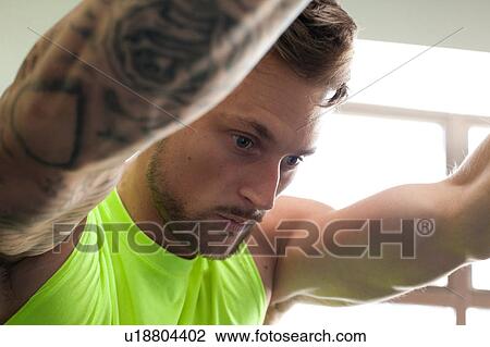 Tattooed man wearing vest looking down View Large Photo Image Stock Image - Tattooed man wearing vest looking down. Fotosearch