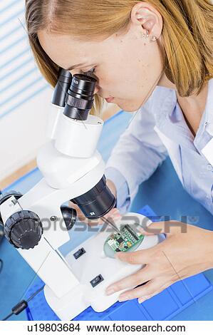 Picture - Technician using microscope. Fotosearch
