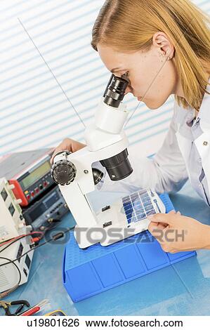 Stock Photograph - Technician using microscope. Fotosearch