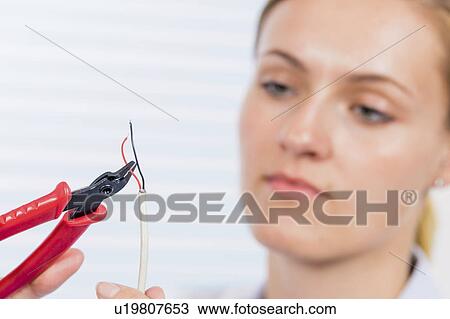 Stock Image - Technician using pair of pliers. Fotosearch