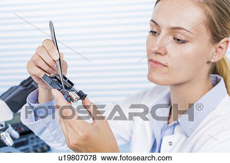 Stock Photo - Technician using working on micro chip. Fotosearch