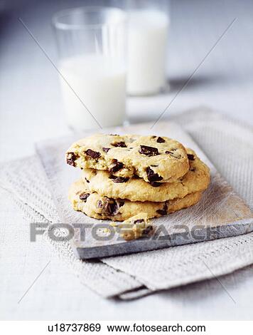Stock Photo - Three chocolate chip cookies with glass of milk. Fotosearch
