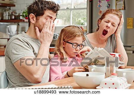 Tired mid adult parents at breakfast table whilst daughter reads newspaper View Large Photo Image Stock Image - Tired mid adult parents at breakfast table whilst daughter reads newspaper. Fotosearch
