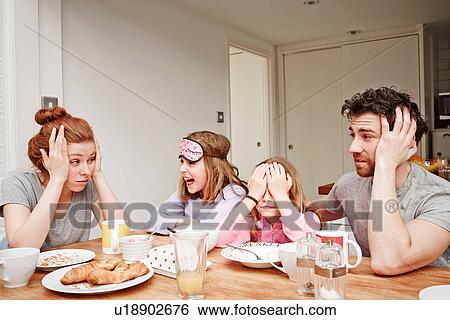 Tired mid adult parents at breakfast table with two daughters View Large Photo Image Stock Photograph - Tired mid adult parents at breakfast table with two daughters. Fotosearch